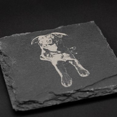 Silberner Hund auf schwarzem Schieferstein.