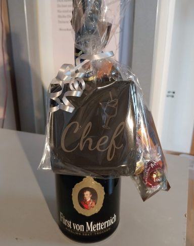 Flasche Champagner mit einem Keks in Form einer Tafel und der Aufschrift "Chef".