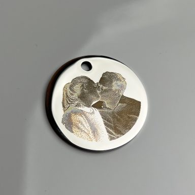 Silberne Medaille mit eingravierten Bildern von einem küssenden Paar.